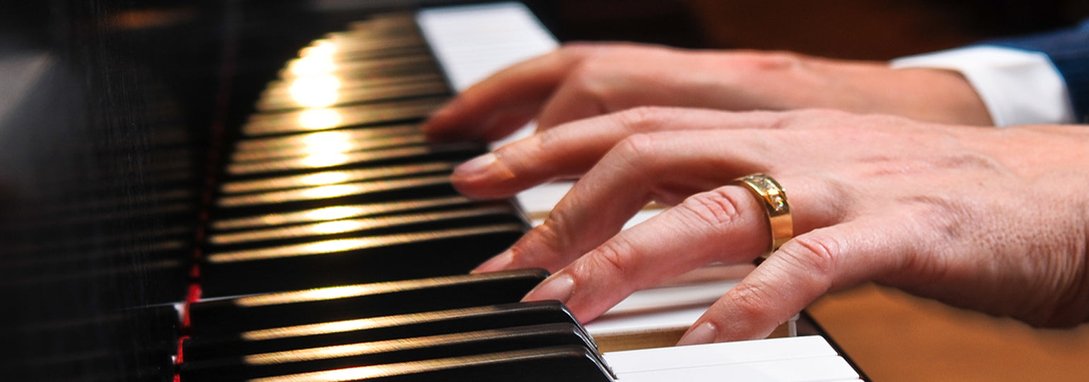 Steinway Artist and Composer Kevin Kern. Closeup of his hands playing piano, his left hand has gold wedding ring on the finger.